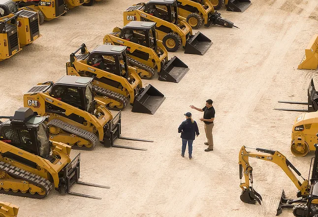 Rows of skid steers staged across an auction yard