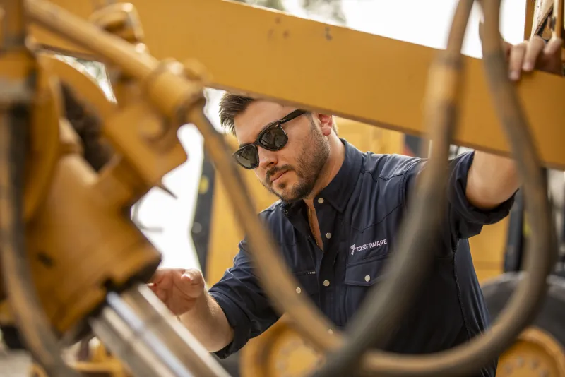 Operator reaching into the linkage of a heavy machine